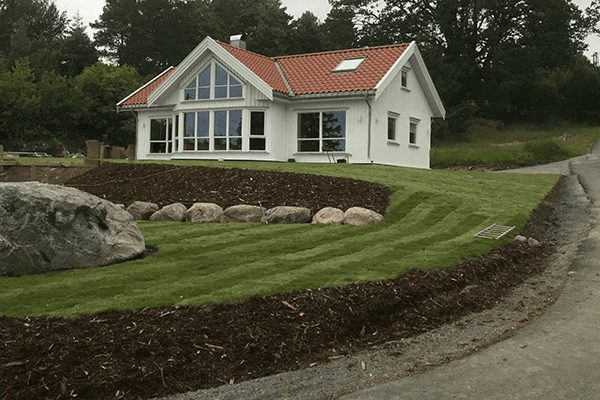 Hvit bolig med ny plen og bark